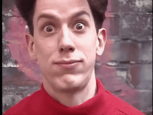 a man in a red shirt is making a funny face with his eyes wide open .