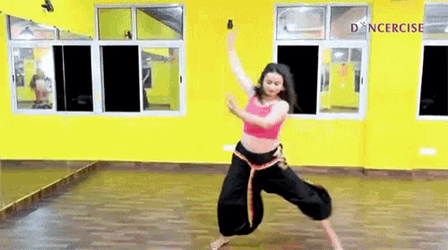 a woman is dancing in a dance studio in front of a yellow wall .