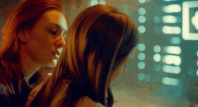 two women are looking at each other in front of a window with the letter e on it