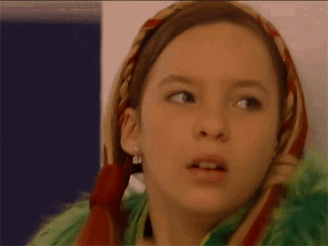 a young girl wearing a green fur coat and a scarf around her head