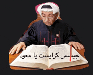 a man is sitting at a table reading a bible in arabic