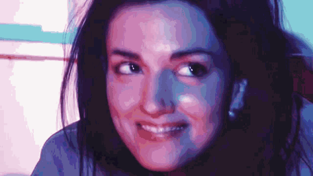 a close up of a woman 's face with a pink and blue background