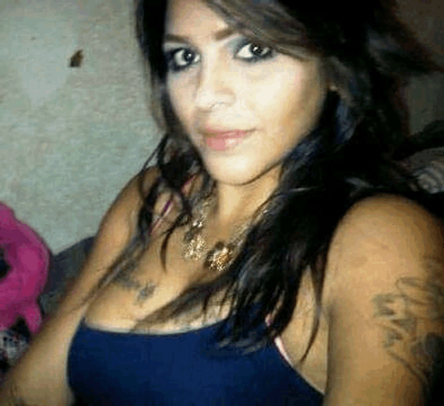 a woman with a tattoo on her arm is taking a selfie in a blue tank top .