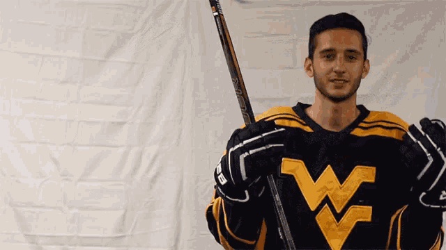 a man in a black and yellow jersey with the letter w on it holds a hockey stick