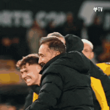 a man in a black jacket is hugging another man in a black jacket