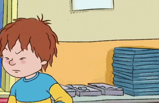 a boy in a blue and yellow shirt is standing in front of a stack of books