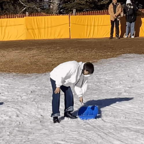 a man in a white sweatshirt is pulling a sled in the snow