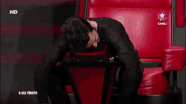 a man is sitting in a chair with his head down and the words hd canli on the screen behind him