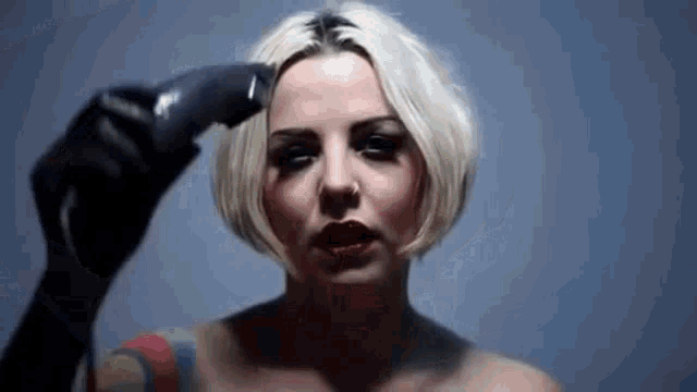 a woman with a tattoo on her arm is holding a razor to her head .