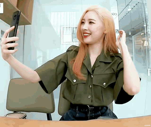 a woman with red hair is taking a selfie with her phone .