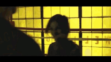 a man and a woman are standing in a boxing ring in front of a window with the letter m on it