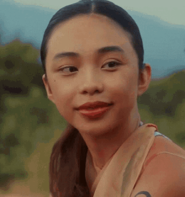 a close up of a woman 's face with a ponytail and a scarf around her neck .