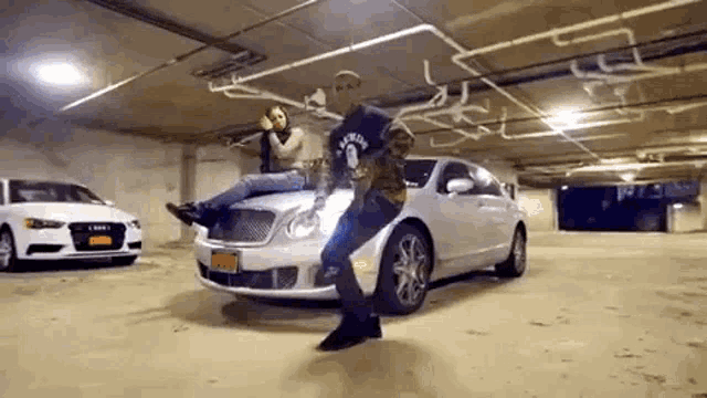 a man is standing on the hood of a white car in a parking garage .