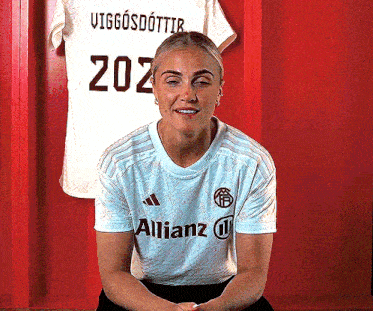 a woman wearing a white adidas shirt with a allianz logo on it