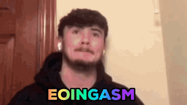 a man with a beard is standing in front of a door with the words eoingasm written on his face
