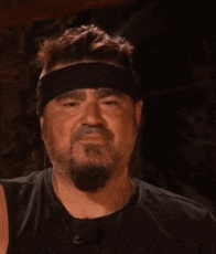 a man with a beard is wearing a headband and making a face .