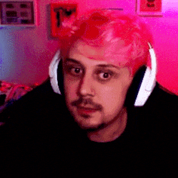 a man with pink hair is wearing headphones in front of a pink wall .
