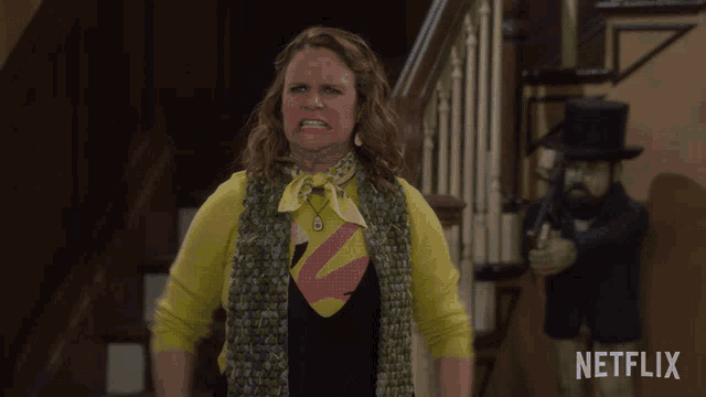 a woman in a yellow sweater stands in front of a netflix lamp