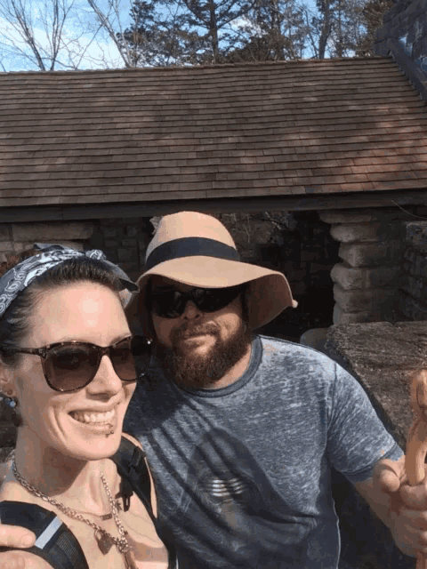 a man and a woman are posing for a picture and the woman is wearing sunglasses