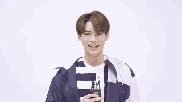 a young man is smiling while holding a walkie talkie in his hand .