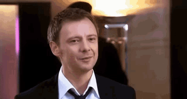 a man in a suit and tie is smiling for the camera .