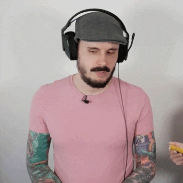 a man wearing headphones and a pink shirt has tattoos on his arms
