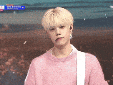 a young man wearing a pink sweater is standing in front of a crowd