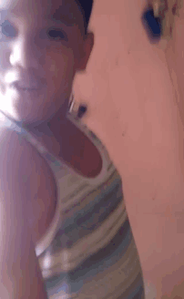 a young boy in a tank top is taking a selfie .