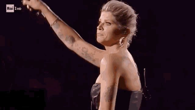 a woman with tattoos is singing into a microphone on a stage .