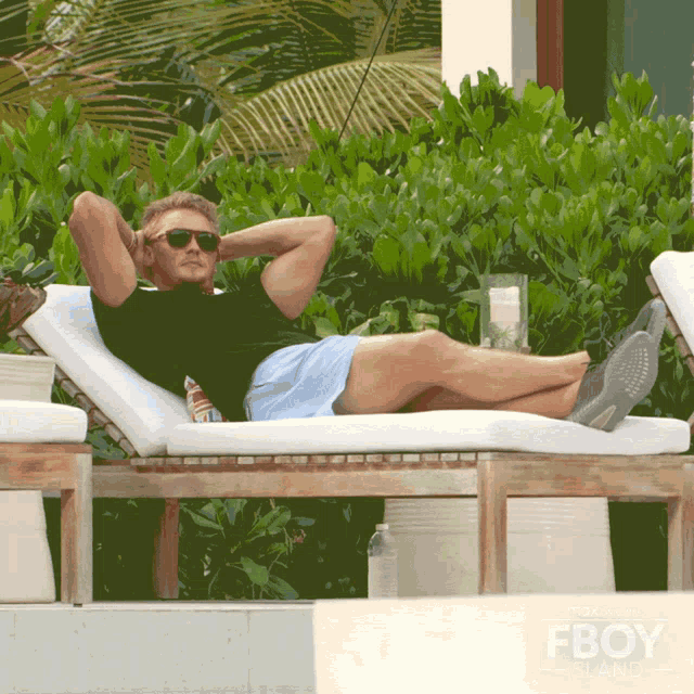 a man is laying on a lounge chair with his legs crossed and a fboy logo in the background