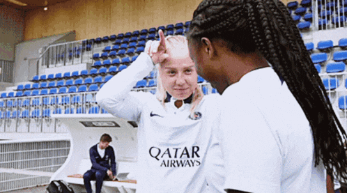 a woman wearing a white qatar airways jersey