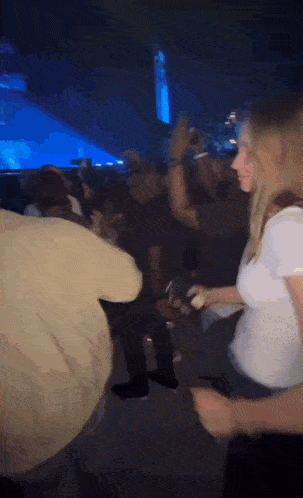 a woman in a white shirt is dancing in a crowd of people at a concert .