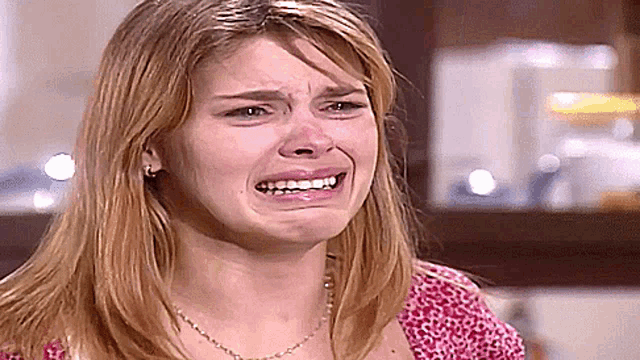 a woman with a necklace is crying and making a funny face