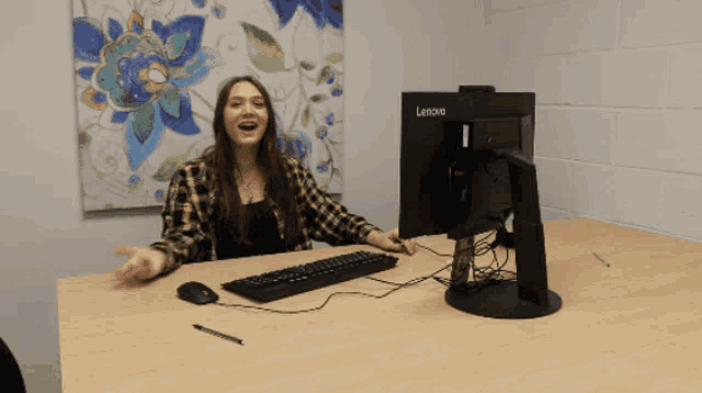 a woman sitting at a desk in front of a lenovo computer