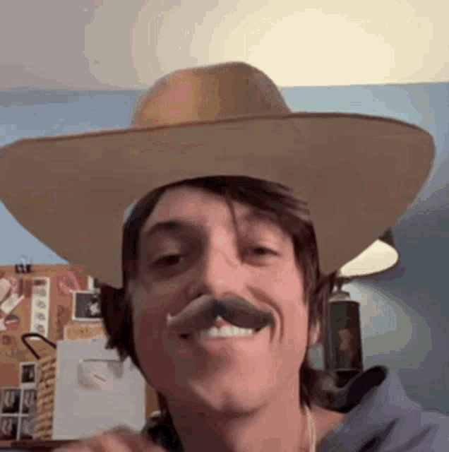 a man with a cowboy hat and mustache is smiling .