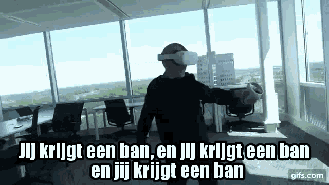 a man is wearing a virtual reality headset and holding a controller in an office .