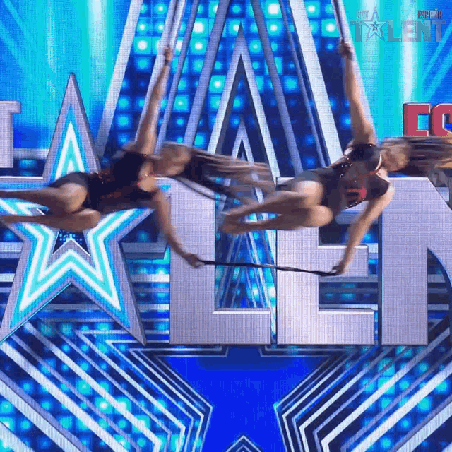 two women are performing aerial acrobatics in front of a sign that says talent