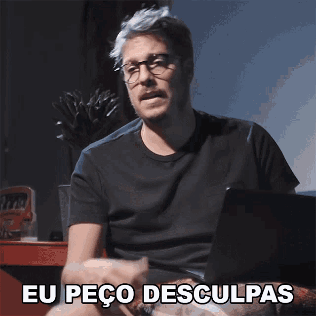 a man sitting in front of a laptop with the words eu peco desculpas below him