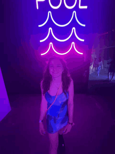 a girl stands in front of a neon sign that says pool