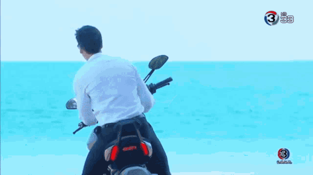a man in a white shirt and tie is standing next to a man on a motorcycle .