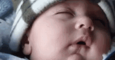 a close up of a baby wearing a hat sleeping .