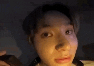a close up of a person 's face with a phone in their hand and looking at the camera .