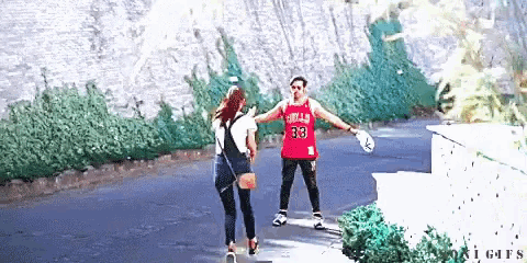 a man in a chicago bulls jersey is holding a woman 's hand