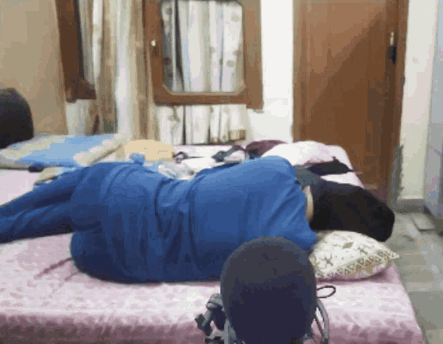 a person is laying on a bed with a blue shirt on