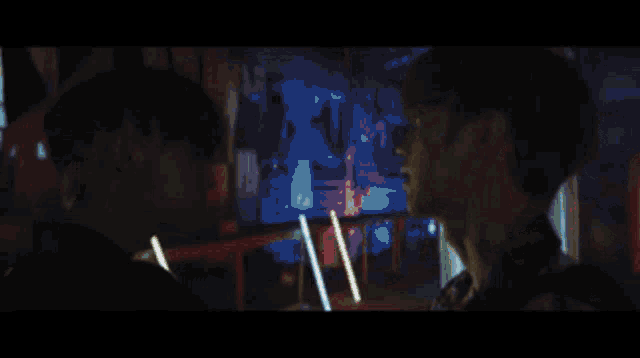 a man and a woman looking at each other in a dark room