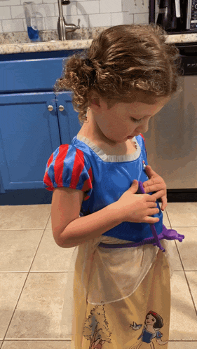 a little girl in a snow white costume is playing with a toy