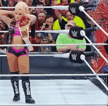 a woman is standing in a wrestling ring wearing a wwe belt