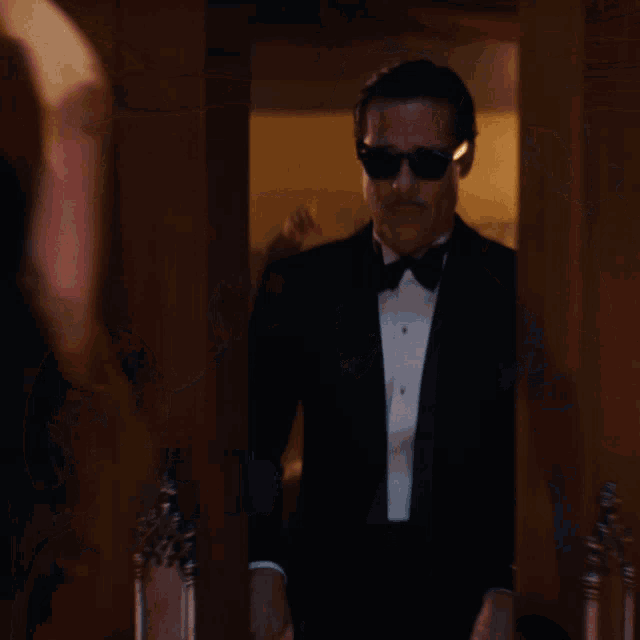 a man wearing sunglasses and a tuxedo is holding a card that says ' i 'm sorry '