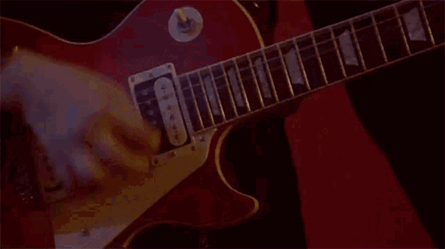 a close up of a person playing a red guitar