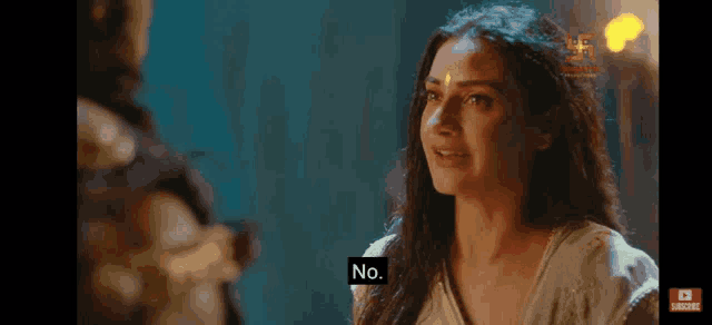 a woman with a bindi on her forehead is talking to a man in a dark room .